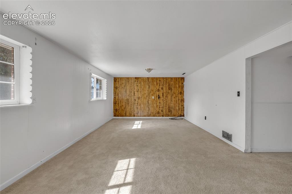 Image 18 of 25: Wood-paneled accent wall with light beige carpeting and white painted walls