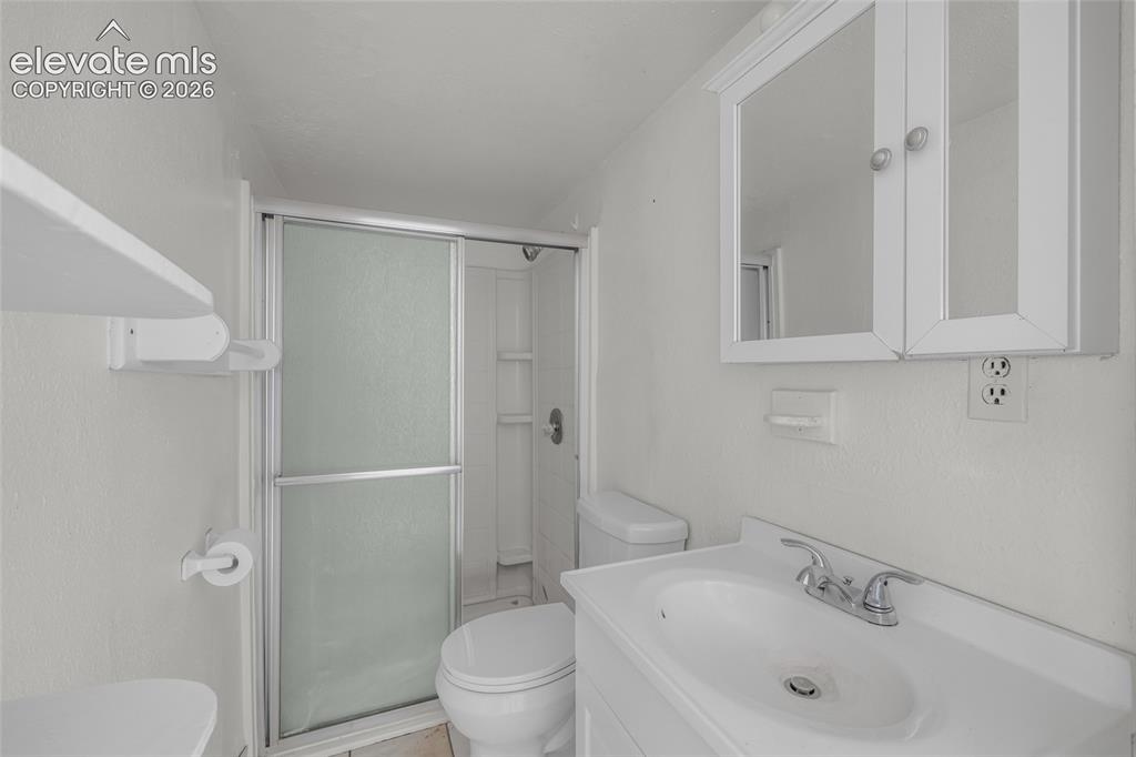 Image 20 of 25: Bathroom featuring a shower stall with sliding frosted glass doors, white v