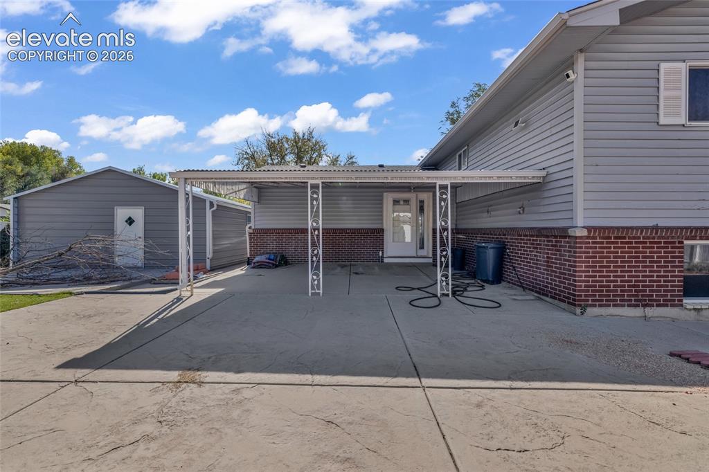 Image 23 of 25: Covered patio with stamped concrete flooring, siding and brick exterior, an
