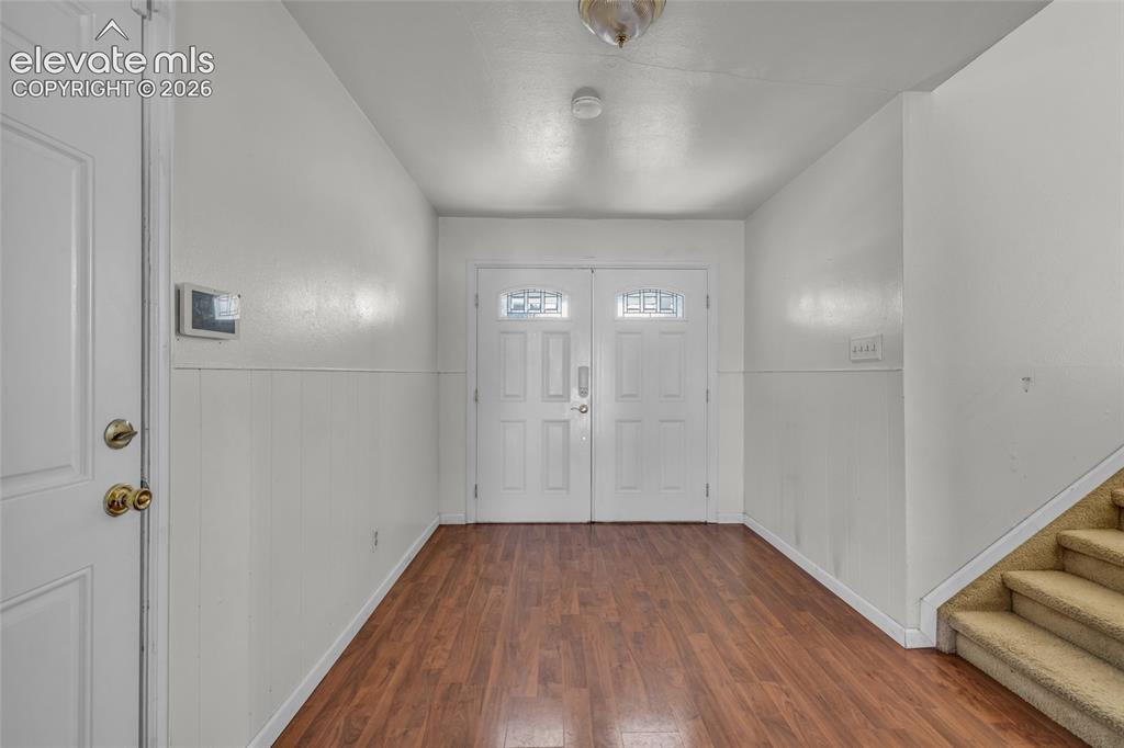 Image 5 of 25: Entryway featuring wood-finish flooring, white wainscoting, and double door