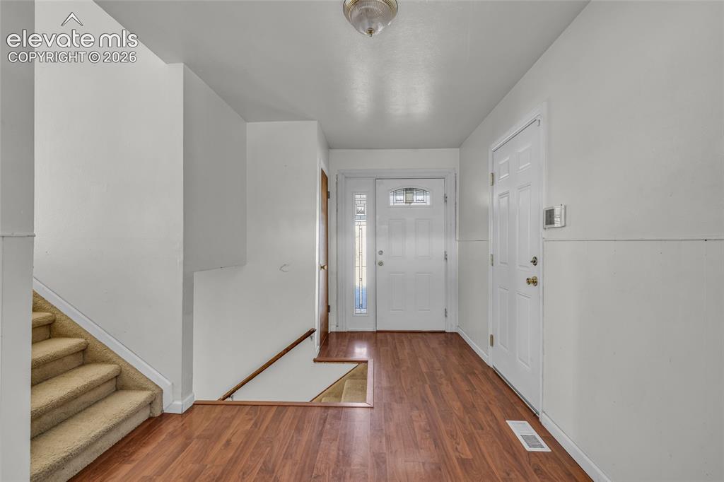 Image 6 of 25: Entryway featuring wood-finish flooring, two panel doors, and a carpeted st