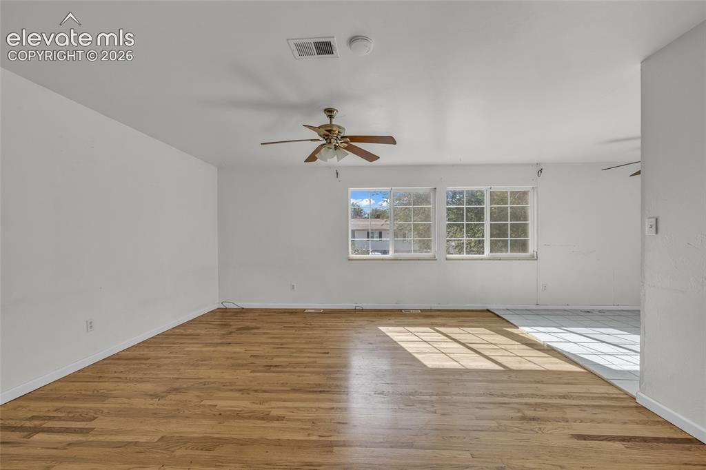 Image 7 of 25: Expansive room featuring wood-finish flooring, white walls, and a ceiling f