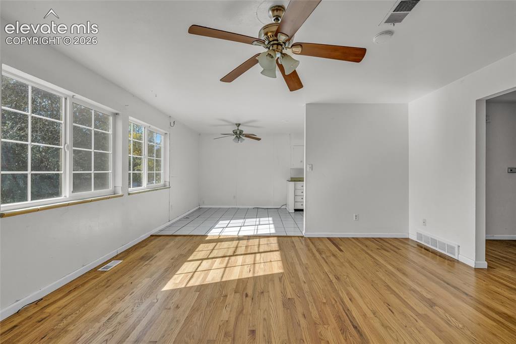 Image 8 of 25: Hardwood flooring, multiple windows, ceiling fans, recessed wall opening, t
