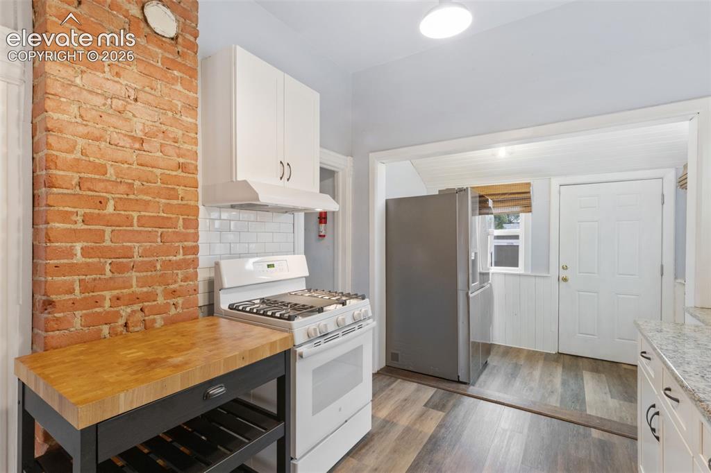 Image 16 of 38: Exposed original brick and gas range