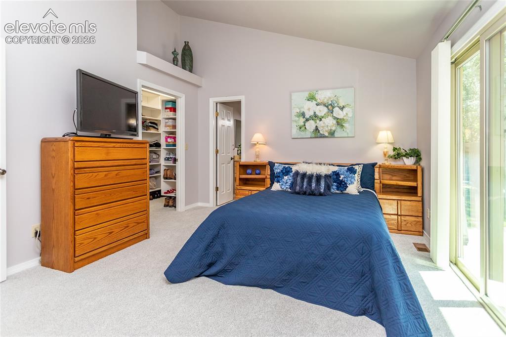 Image 23 of 48: Carpeted interior room featuring a vaulted ceiling with a high shelf, a bui