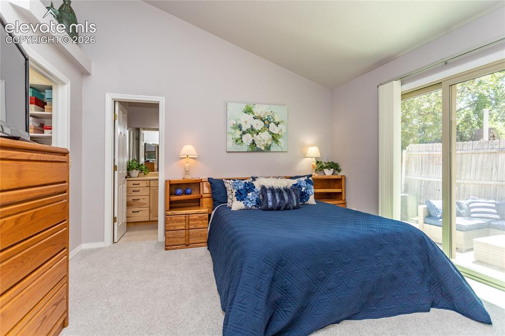 Image 24 of 48: Spacious primary bedroom featuring vaulted ceilings and sliding glass door 