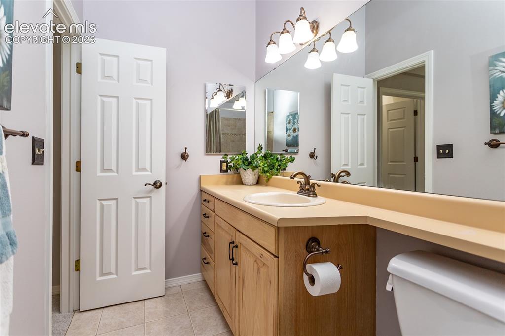 Image 26 of 48: Bathroom featuring a spacious vanity with integrated sink, a large mirror, 