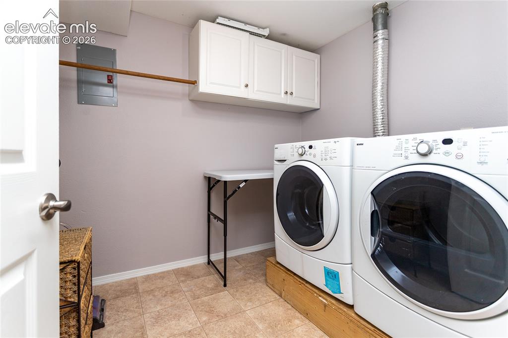 Image 37 of 48: Laundry room in basement with storage cabinets and drying rod 