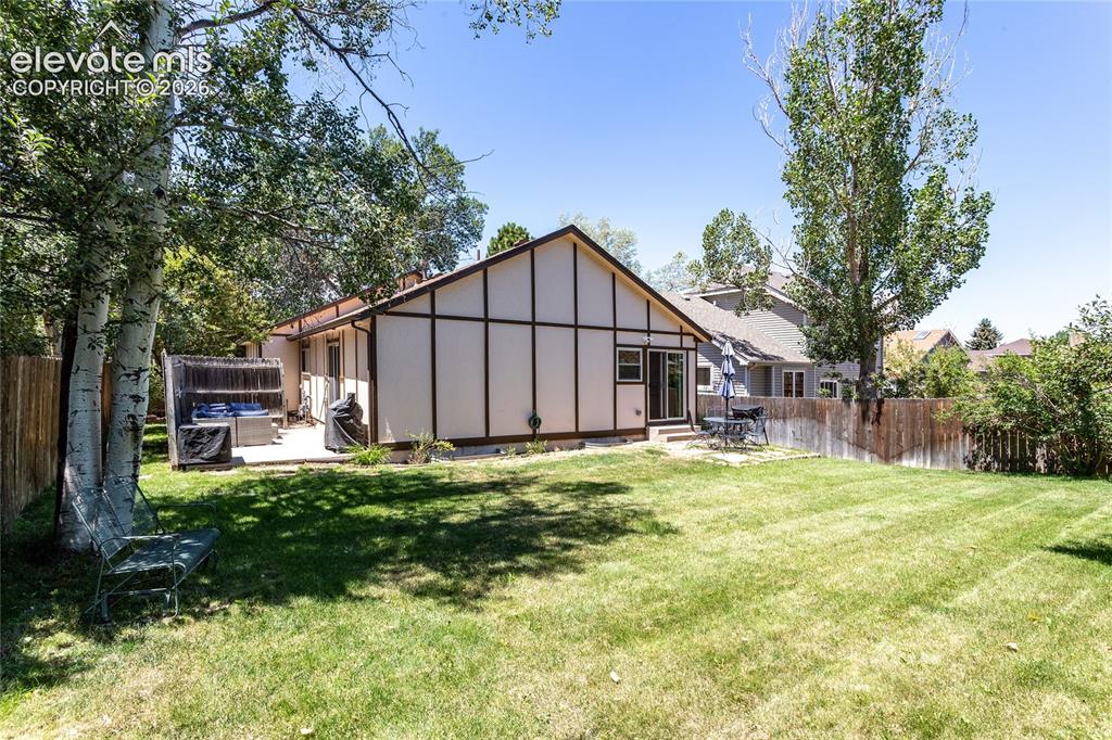 Image 43 of 48: Expansive backyard with a manicured lawn, bordered by a wood fence