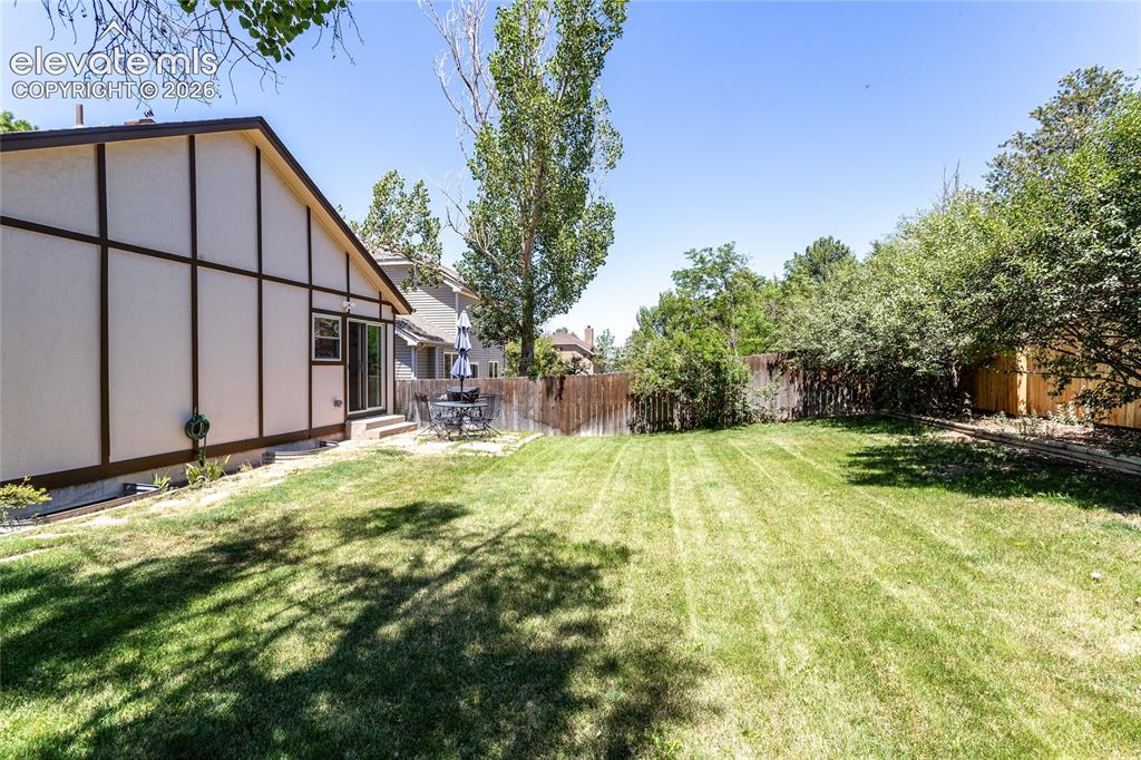 Image 44 of 48: Expansive backyard featuring a lush lawn, mature trees providing natural sh
