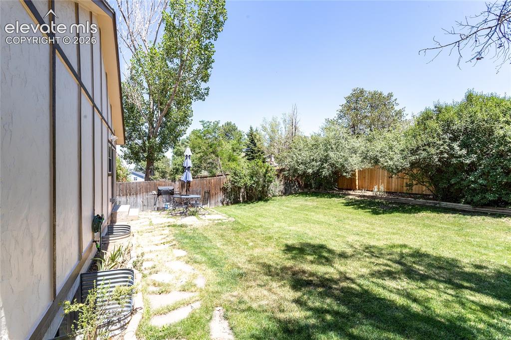 Image 45 of 48: Expansive backyard featuring a lush lawn, mature trees, and a flagstone pat