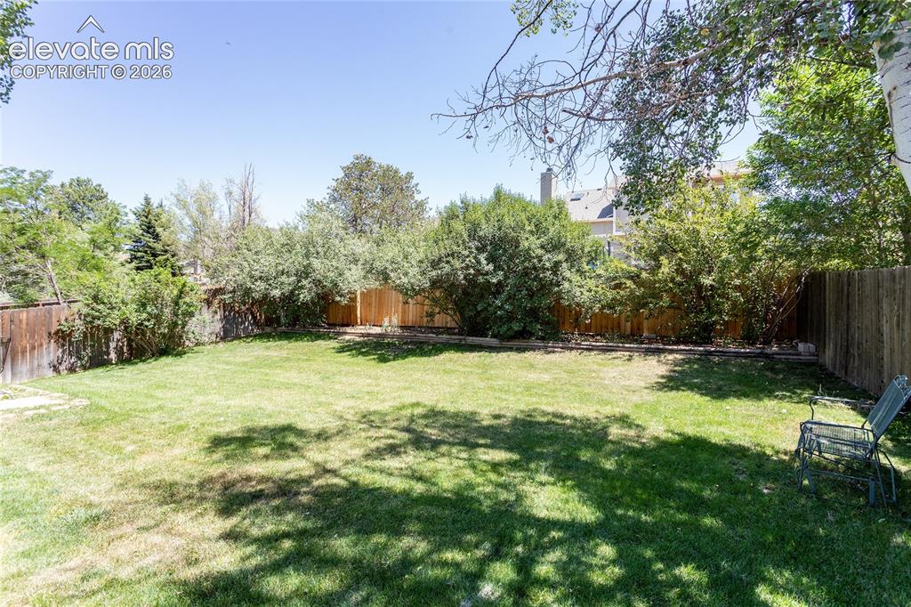 Image 46 of 48: Expansive grassy yard with mature perimeter trees and wood fencing