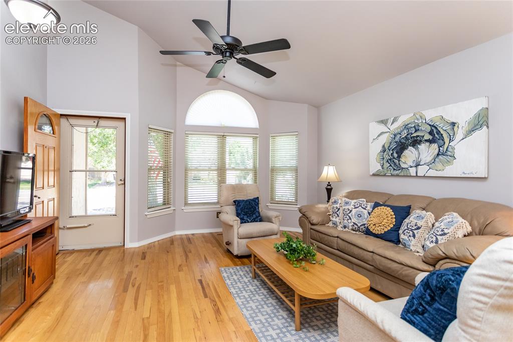 Image 6 of 48: Living area featuring vaulted ceilings and wood-finish flooring