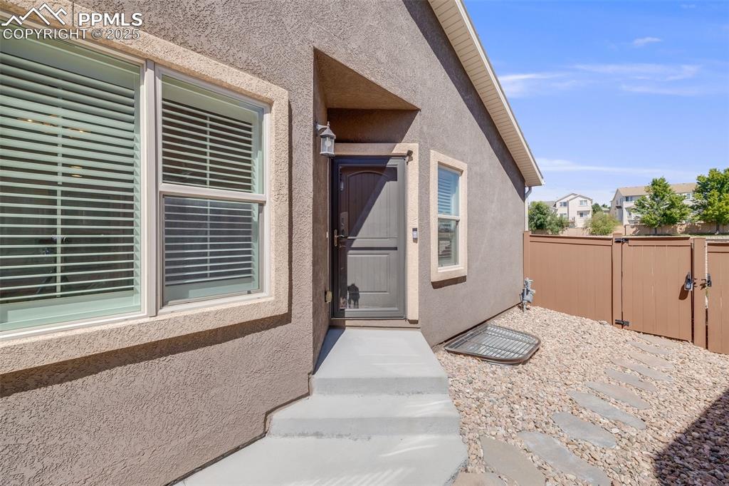 Image 5 of 44: Property entrance with stucco siding and a gate