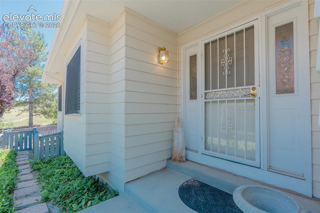 Image 4 of 46: Front entry featuring an exterior wall sconce, a security screen door with