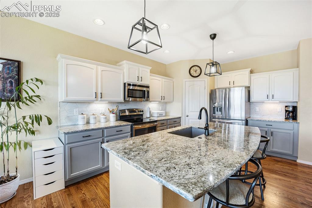 Image 13 of 50: Kitchen featuring decorative backsplash, decorative light fixtures, stainle