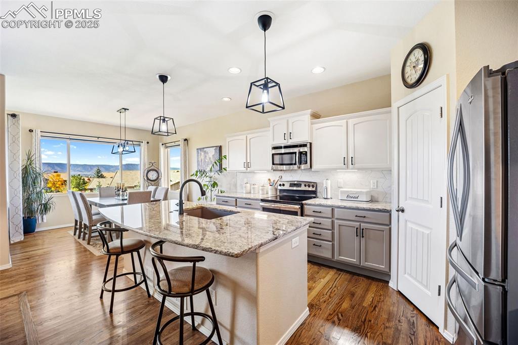 Image 15 of 50: Kitchen featuring backsplash, stainless steel appliances, decorative light 