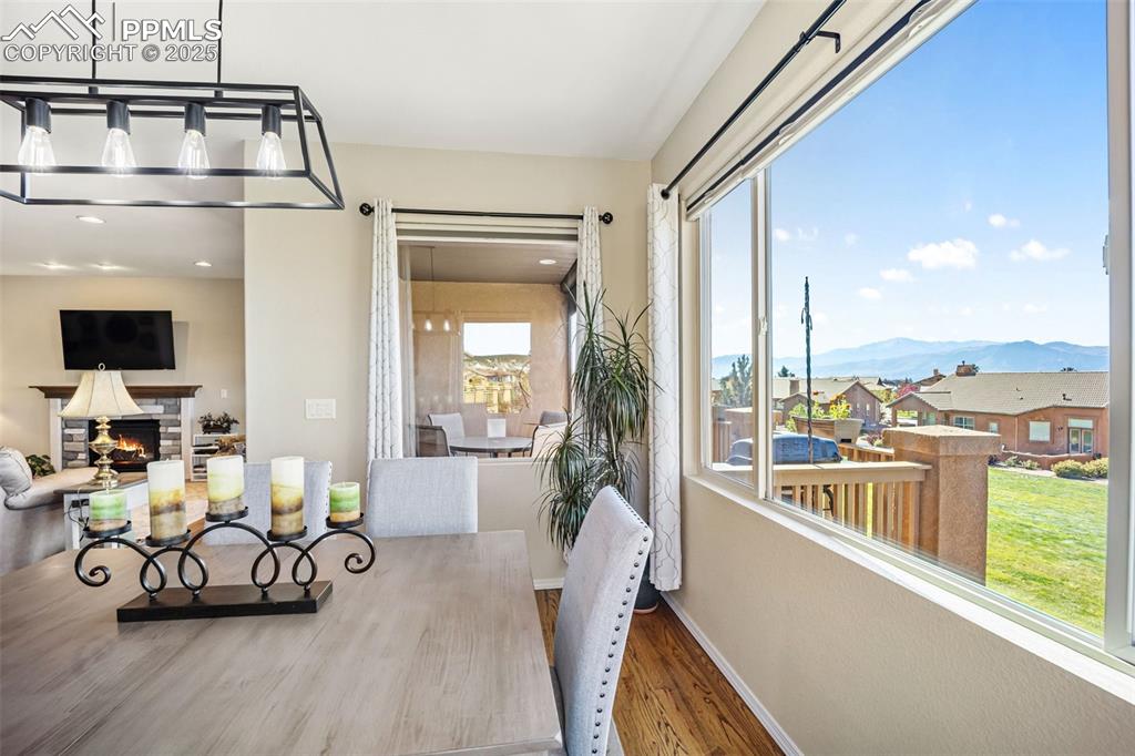 Image 19 of 50: Dining space featuring a residential view, a lit fireplace, wood finished f