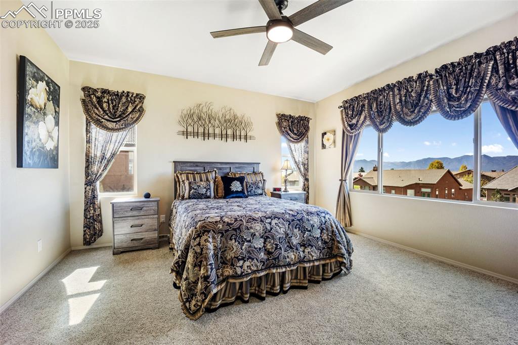 Image 22 of 50: Carpeted bedroom with a mountain view and a ceiling fan