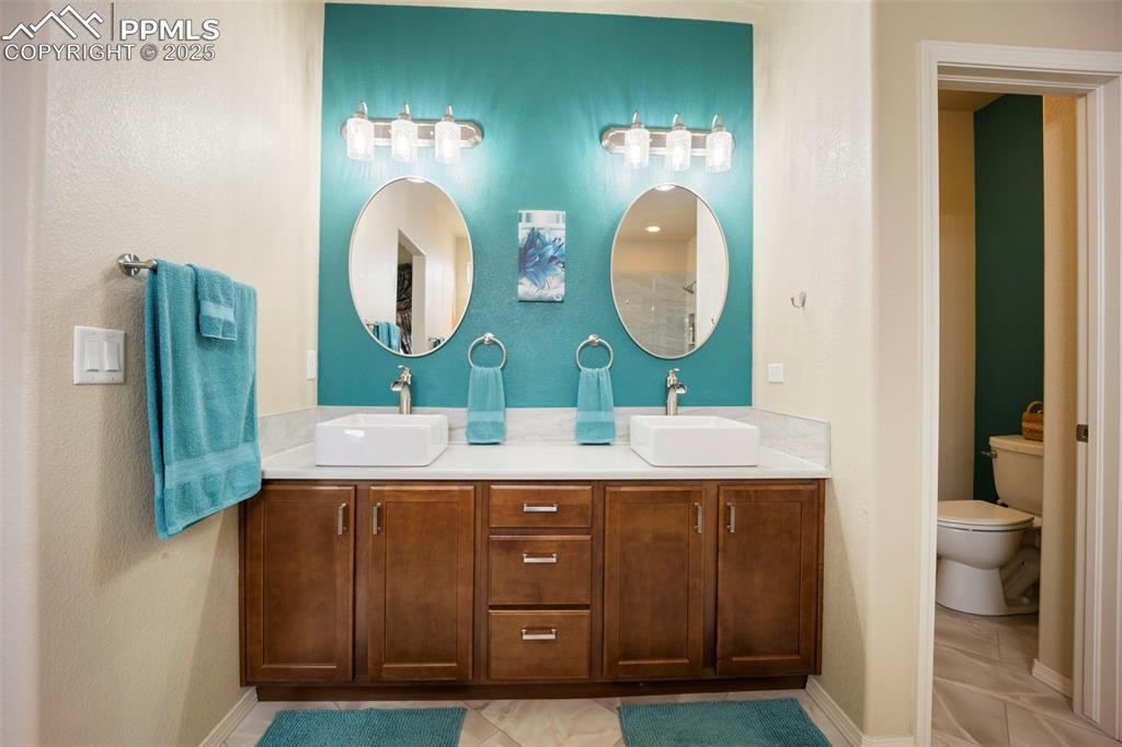 Image 25 of 50: Bathroom featuring double vanity, light tile patterned flooring, and a text