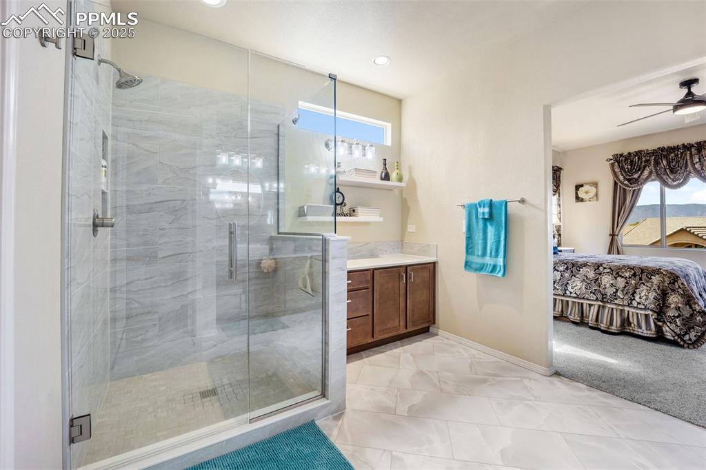 Image 27 of 50: Ensuite bathroom with a shower stall, vanity, ceiling fan, light tile patte