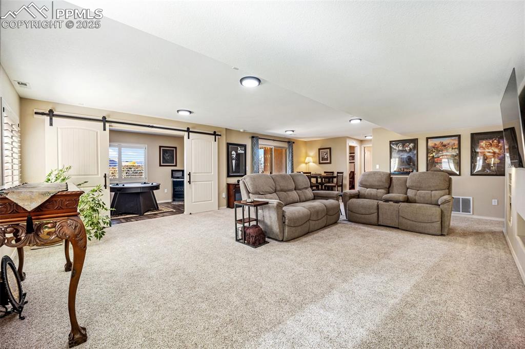 Image 29 of 50: Living area with a barn door and carpet floors