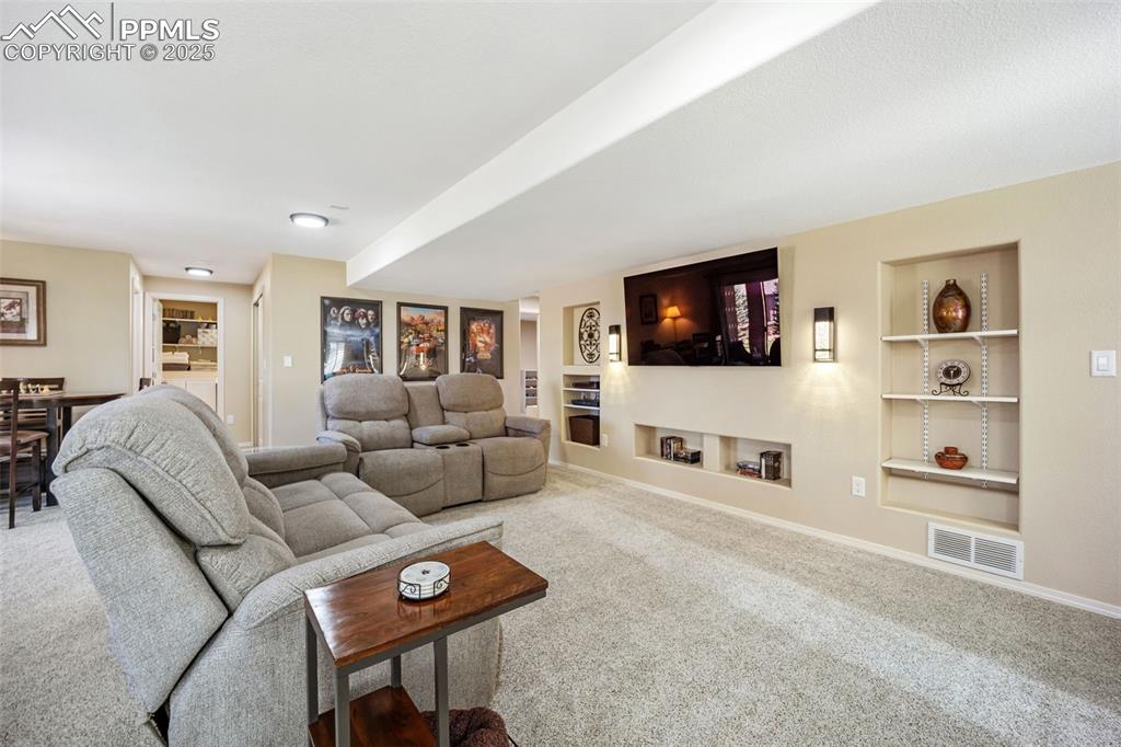 Image 30 of 50: Carpeted living area featuring built in shelves and baseboards