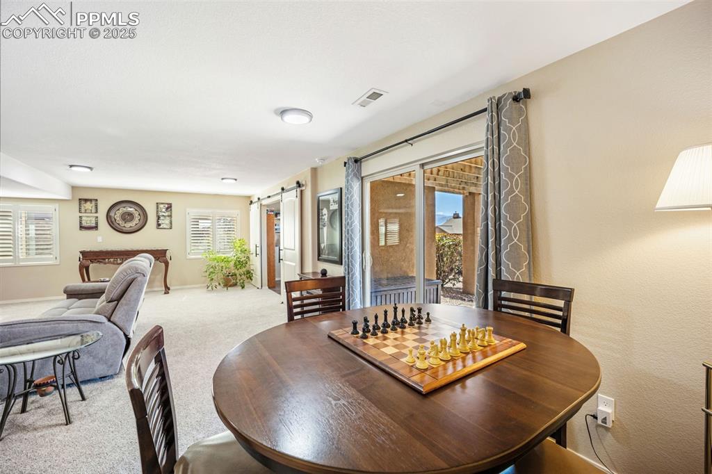 Image 33 of 50: Carpeted dining space featuring a barn door and healthy amount of natural l