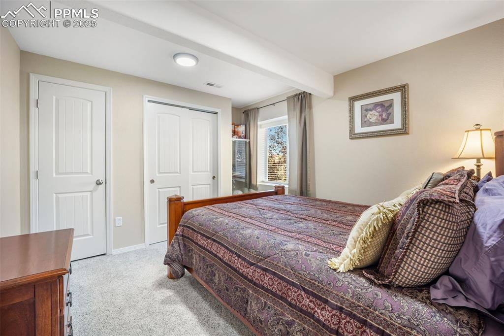 Image 34 of 50: Bedroom featuring light colored carpet, a closet, and beamed ceiling