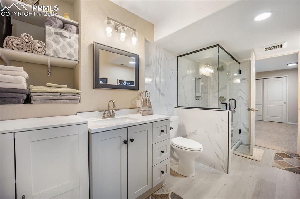 Image 36 of 50: Bathroom with a marble finish shower, vanity, and recessed lighting