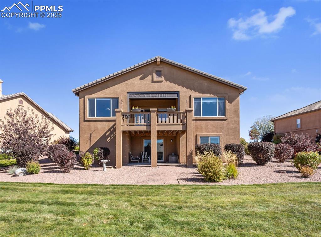 Image 42 of 50: Back of property with a patio area, stucco siding, and a lawn