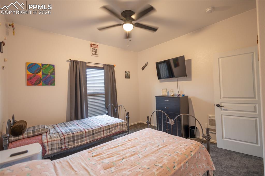 Image 29 of 34: Bedroom with dark colored carpet and a ceiling fan