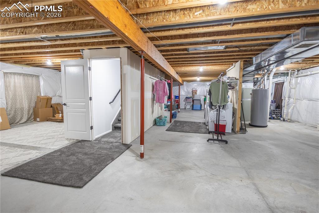 Image 30 of 34: Unfinished below grade area with water heater, stairway, and drainage syste