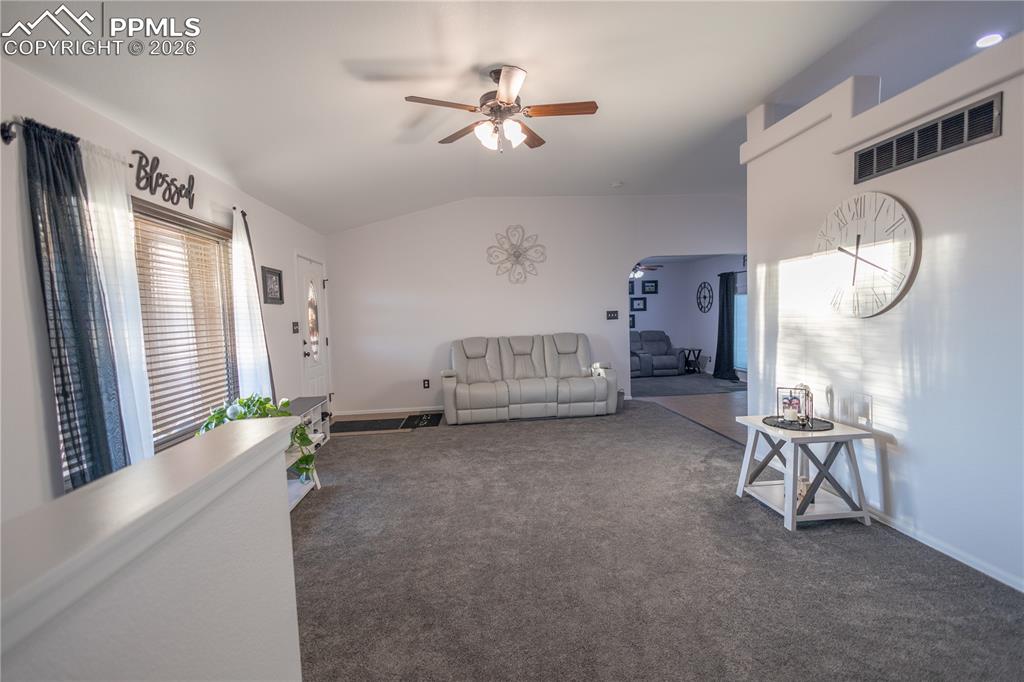 Image 6 of 34: Carpeted living room with lofted ceiling and ceiling fan