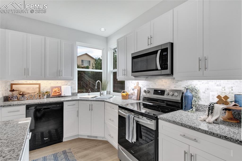 Image 10 of 44: Kitchen with appliances with stainless steel finishes, white cabinets, tast