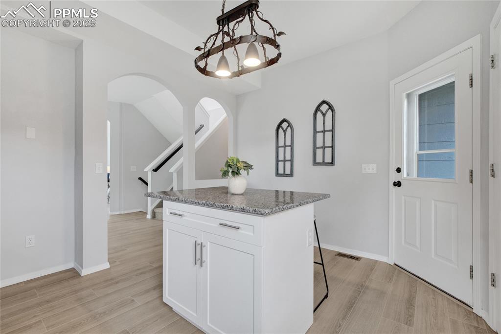 Image 12 of 44: Kitchen featuring a kitchen island, light stone counters, arched walkways, 