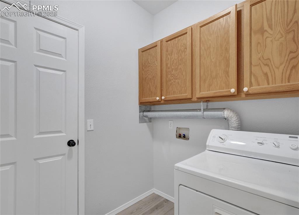 Image 19 of 44: Washroom featuring cabinet space, washer / dryer, and light wood-type floor