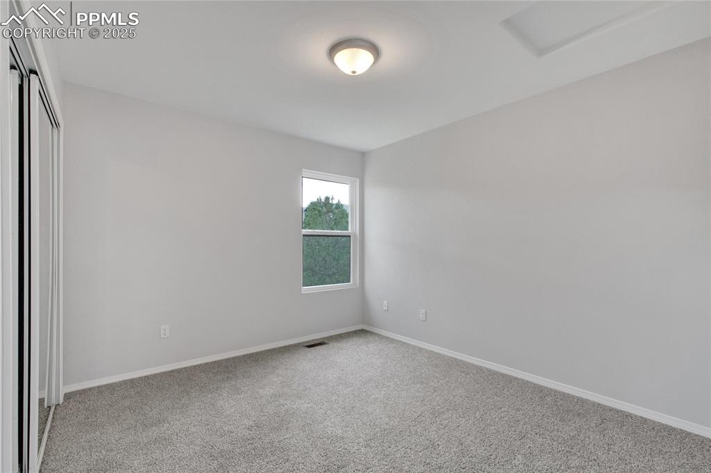 Image 25 of 44: Carpeted spare room featuring attic access and baseboards