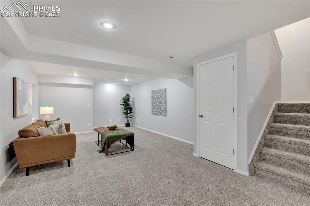 Image 27 of 44: Carpeted living area with stairway and recessed lighting
