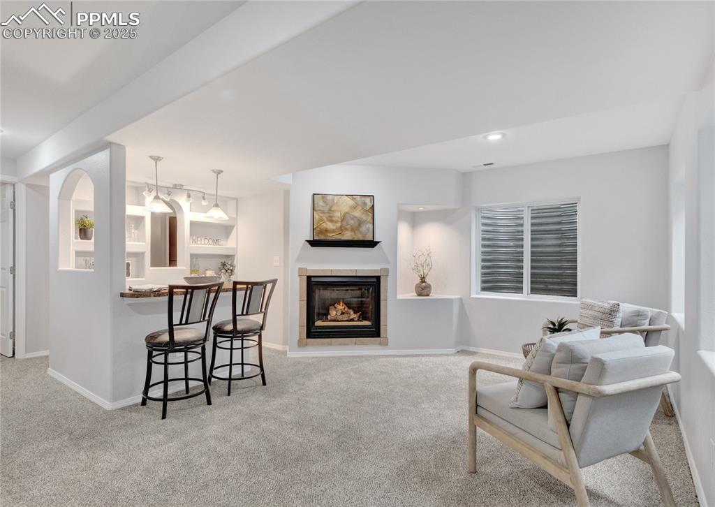 Image 29 of 44: Carpeted living room with a tiled fireplace and recessed lighting