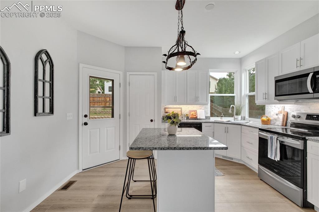 Image 8 of 44: Kitchen with appliances with stainless steel finishes, backsplash, stone co