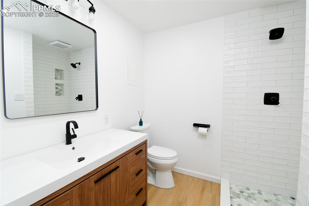 Image 14 of 25: Full bathroom with vanity, light wood-style flooring, and a tile shower