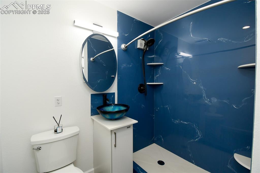 Image 17 of 25: Full bathroom with a marble finish shower and vanity