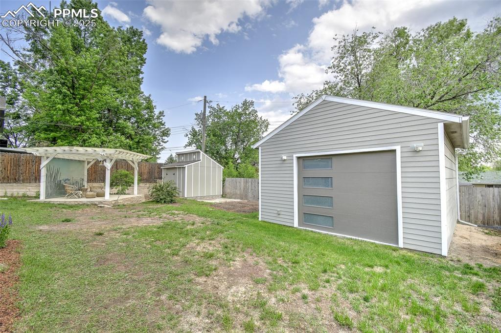 Image 20 of 25: Fenced backyard featuring a pergola, a patio, and a storage shed