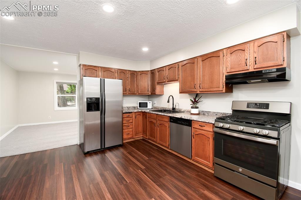 Image 5 of 25: Kitchen with stainless steel appliances, recessed lighting, dark wood-style