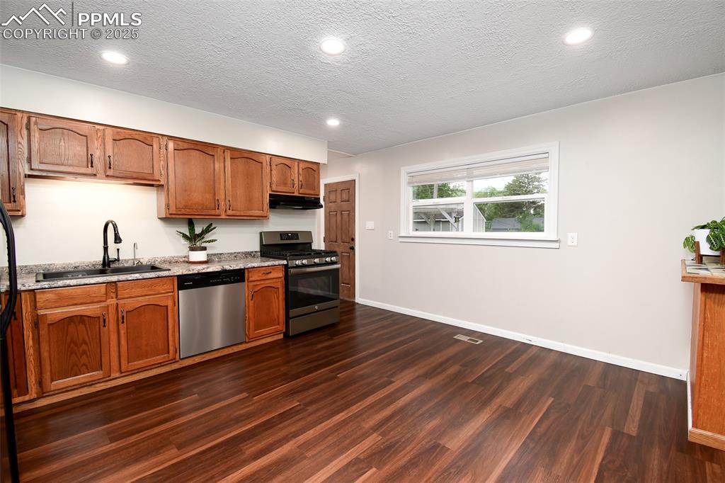Image 6 of 25: Kitchen with stainless steel appliances, a textured ceiling, recessed light