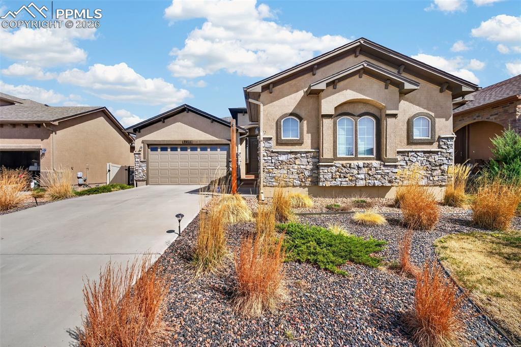 Image 1 of 34: View of front of home featuring stucco siding, concrete driveway, stone sid