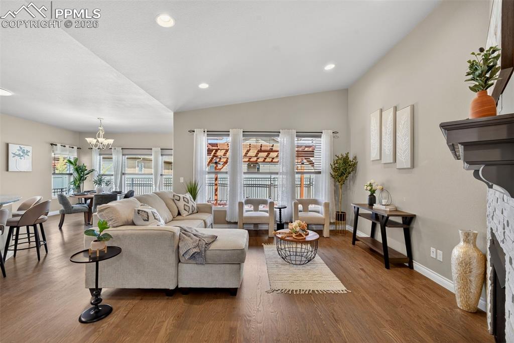 Image 10 of 34: Living area featuring vaulted ceiling, suspended lighting, wood finished fl
