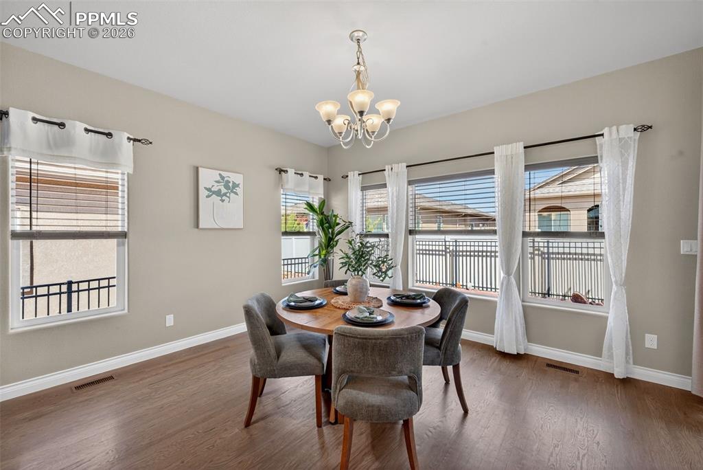 Image 11 of 34: Dining room with suspended lighting and dark wood-style flooring