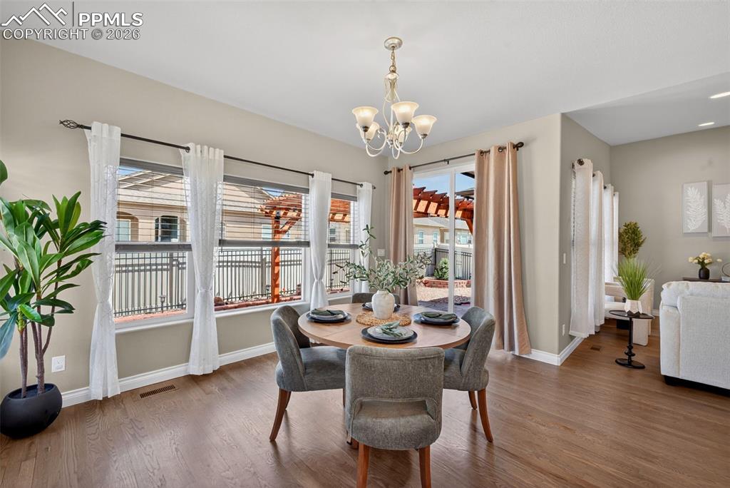 Image 12 of 34: Dining space featuring wood finished floors and hanging lights